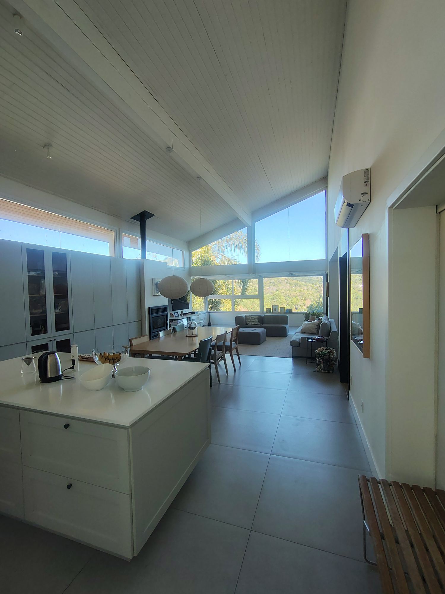 Sala de estar e cozinha integradas, com pé-direito duplo em madeira e vista para as montanhas